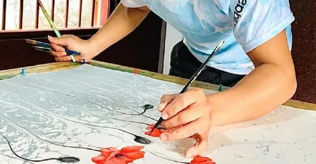 Nghệ nhân đang vẽ tay trên khăn lụa trong quá trình chế tác thủ công tại SenSilk